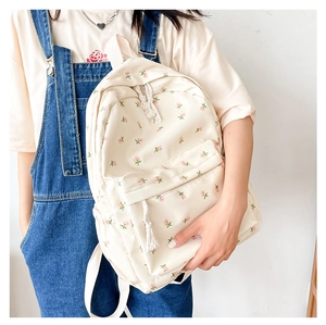 Detail view of cream canvas backpack with pink floral print on a model wearing denim
