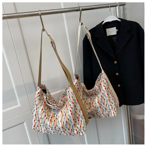 Detail of colorful woven hobo bag with a leather strap and side fabric label