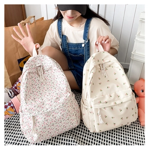 Detail view of floral canvas backpacks with tassel zippers and side pockets for storage