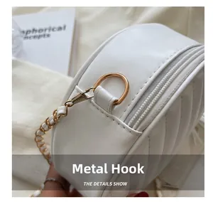 Close-up of white round quilted bag with gold metal D-ring hook and woven chain strap