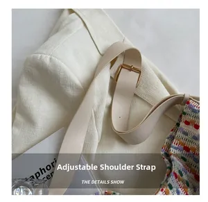 Detail of multi-color woven tote bag featuring an adjustable white leather shoulder strap