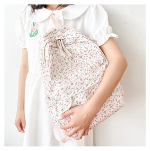 Detailed close-up of a floral canvas backpack with pink flower patterns and cream straps