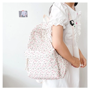 Detail view of white floral canvas backpack with pink flower patterns and zip pocket