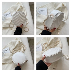 Detail view of white round crossbody bag featuring V-quilted texture and tassel zipper