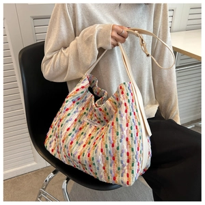 Close-up of a colorful woven tote bag featuring striped textures and a faux leather strap
