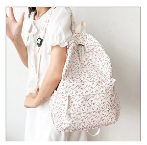Detail of pink floral canvas backpack with braided rope zipper and adjustable straps