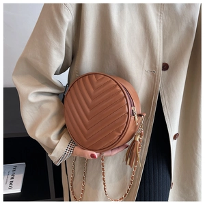 Detail of brown round crossbody bag with V-shaped quilting and gold chain tassel