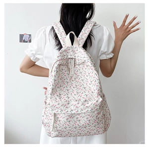 Close-up of white canvas backpack featuring detailed pink floral patterns and side pocket