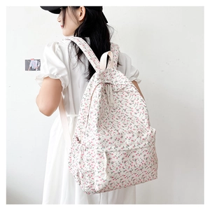 Side view of floral canvas backpack on shoulder with pink flower patterns and white base