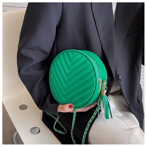 Detail of green round crossbody bag with V-shaped quilting and gold tassel zipper