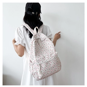 Detailed back view of a white canvas backpack featuring a delicate pink floral pattern