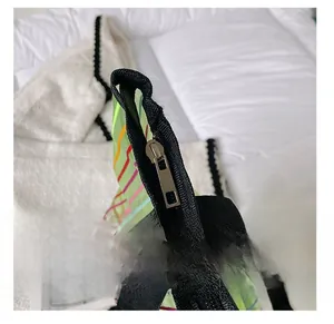 Détail du zip noir fluide sur un grand sac cabas en maille verte semi-transparente