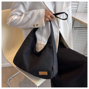Close-up of black canvas tote bag showing the brown leather sport label and side tag