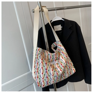 Detail of colorful woven tote bag with wide white strap and golden metal buckle