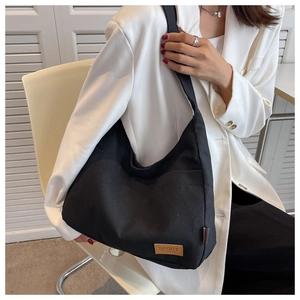 Detail of a minimalist black canvas tote bag showing the textured fabric and sport label tag