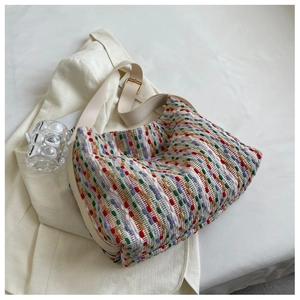 Detail of colorful rainbow woven tote bag featuring wide faux leather strap and golden hardware
