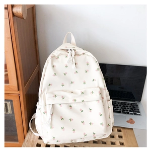 Close-up of cream floral backpack with pink rose patterns on a wooden surface