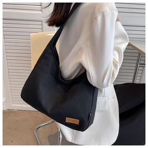 Detail of black canvas tote bag with brown leather logo patch and sports fashion label