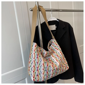 Detail of colorful knitted tote bag with wide brown leather strap and brand label