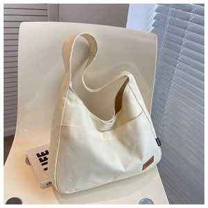 Detailed macro of cream canvas tote bag with brown leather patch on a stylish white chair