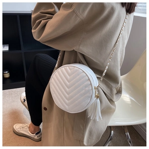 Detail of white round crossbody bag with V-quilted texture and elegant tassel accent