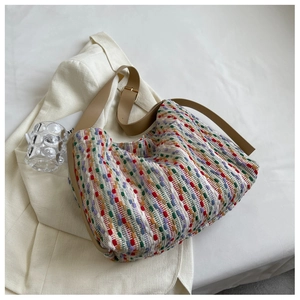 Detail of colorful woven tote bag texture with brown strap and metal buckle on white suit