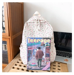 Detailed view of cream floral backpack featuring sturdy top handle and woven zipper pullers