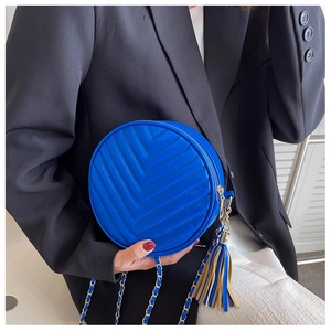 Close-up of electric blue round chain bag with V-quilted stitching and dual-tone tassel
