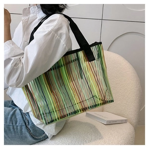 Détail du grand sac cabas à rayures colorées et anses noires porté par un mannequin