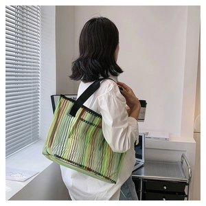 Détail d'un grand sac cabas en filet à rayures colorées et bandoulières en toile noire