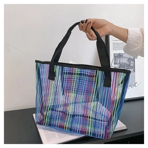 Détail de la texture en maille à rayures colorées et de l'anse noire du sac fourre-tout