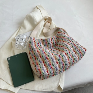 Large colorful woven tote bag with white leather strap on light blazer background