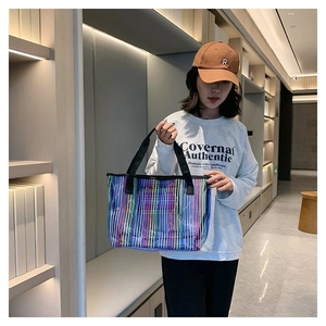 Détail du sac cabas transparent à rayures néon avec des anses noires en tissu