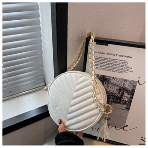 Detail showing white round crossbody bag with V-shaped quilting and gold chain strap
