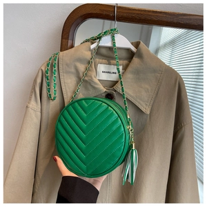 Detailed close-up of green round crossbody bag with V-quilted texture and leather tassel