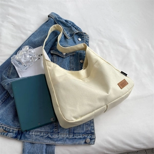 Minimalist beige canvas tote bag with brown SPORT logo placed on blue denim