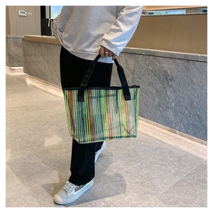 Détail du grand sac cabas en maille rayée colorée avec poignées en nylon noir robuste