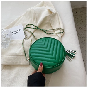 Close-up of green round crossbody bag with V-quilted stitching and metal chain strap