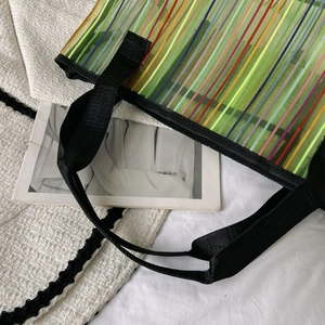 Détail du sac cabas en maille rayée avec poignées en nylon noir et texture transparente