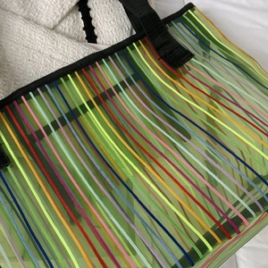 Gros plan du sac cabas en maille verte translucide avec broderie rayée multicolore
