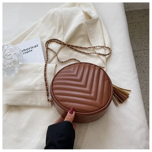 Detail of vintage brown circular crossbody bag with V-shaped quilting and tassel