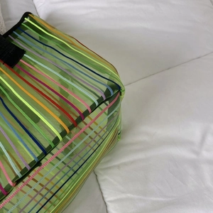 Gros plan détaillé du sac cabas en maille verte translucide avec des rayures arc-en-ciel