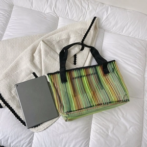 Détail d'un grand sac cabas transparent en PVC avec rayures colorées et anses noires