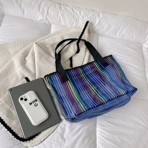 Détail du sac cabas en maille bleue semi-transparente avec rayures colorées et anses noires