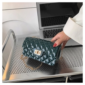 Detail of dark green quilted leather bag with golden turn-lock and chain strap