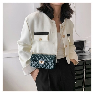 Close-up of a dark green quilted chain bag with gold lock worn with a chic outfit