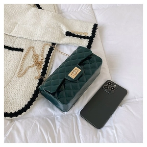 Detail of dark green quilted chain bag with gold square lock and glossy finish