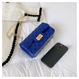 Detail of royal blue quilted jelly bag with gold chain and twist lock on white bedding