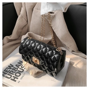 Detail of black quilted patent leather bag with gold chain strap and twist-lock closure