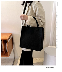 Close-up of black crocodile-embossed tote bag with twin handles and minimalist design